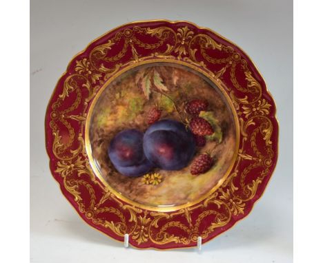 A Royal Worcester shaped circular plate, painted by Richard Seabright, with plums and raspberries, the claret border with gil