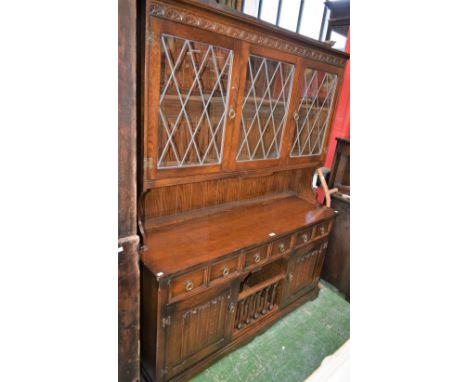 A 20th century oak dresser, outswept cornice above a pair of glazed doors enclosing a shelf, the projecting base with three s