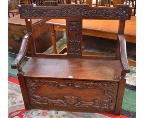 A Victorian oak hall bench/settle, the cresting rail applied with scrolling foliage, the hand rests conforming, rectangular s