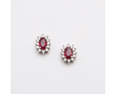 each earring mounted with an oval-shaped ruby within a surround of circular-cut diamonds, in 18ct gold, 2.8 grams. *CR With s