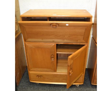 An Ercol teak bureau, fall front enclosing pigeon holes, central cupboard of two shelves, one long drawer shaped  and skirted