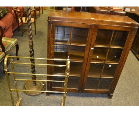 A 1930's oak glazed panel bookcase, enclosing four shelves; an oak free standing barley twist lamp; an early gilt brass towel