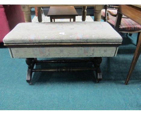 AN EDWARDIAN MAHOGANY DUET STOOL the rectangular upholstered hinged seat on ring turned supports and scroll legs with casters