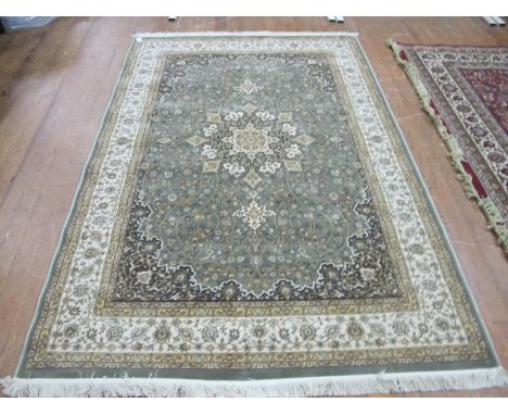 A WOOL RUG the light green and beige ground with central floral panel within a conforming border 237cm x 157cm