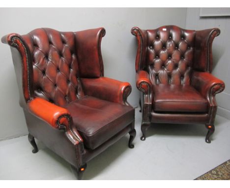 A FINE PAIR OF RED HIDE UPHOLSTERED WING LIBRARY CHAIRS each with a deep button upholstered back and seat with loose cushion 