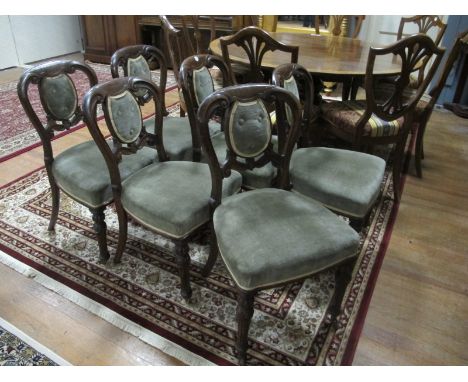 A SET OF SIX VICTORIAN OAK DINING CHAIRS each with a curved top rail above a button upholstered panel and seat on reeded and 