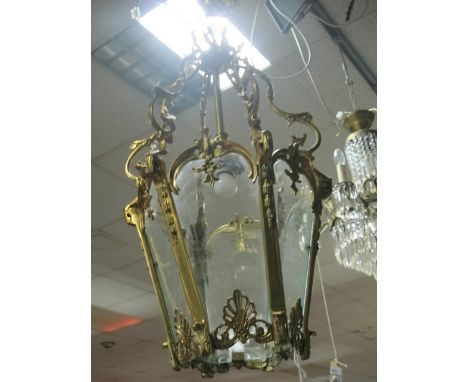 A GILT BRASS SINGLE LIGHT HALL LANTERN with glazed panels on scroll arms