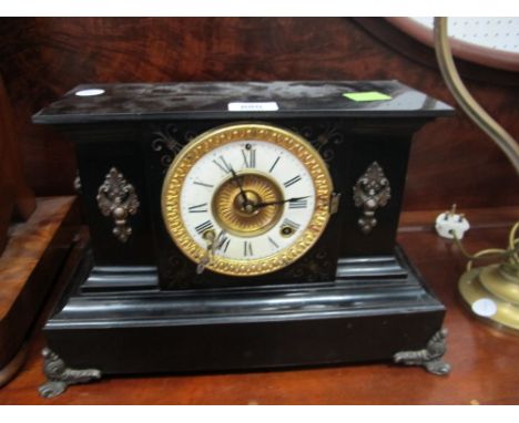 A BLACK METAL MANTLE CLOCK the rectangular case containing a porcelain dial with Roman numerals above a set base with scroll 