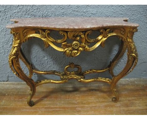 A CONTINENTAL GILTWOOD CONSOLE TABLE of serpentine outline surmounted with a rouge vein marble top above a flowerhead and scr