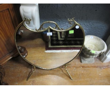 A BRASS AND MIRRORED FIRESCREEN of shield outline with carrying handle raised on splayed legs 77cm (h) x 60cm (w)