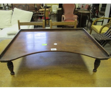 A VICTORIAN MAHOGANY BED TRAY of rectangular concave outline with moulded gallery raised on turned legs 20cm (h) x 72cm (w) x