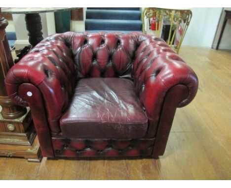 A WINE HIDE UPHOLSTERED LIBRARY CHAIR with deep button upholstered roll over back and arms with loose cushion on casters