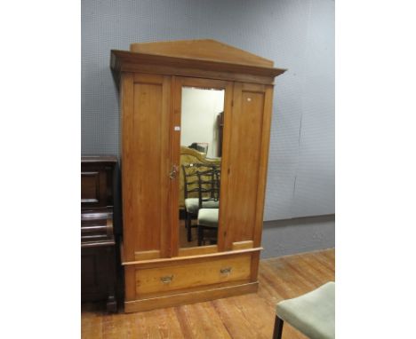 A PINE WARDROBE the architectural pediment above a mirrored door containing hanging rail the base with deep drawer 217cm (h) 