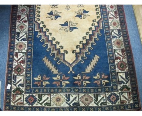 A WOOL RUG the indigo and light pink ground with central panel with hooks and palmets with a conforming border 220cm x 110cm