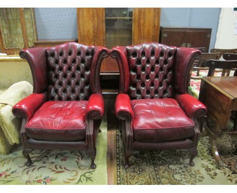 A PAIR OF WINE HIDE UPHOLSTERED WING LIBRARY CHAIRS each with a deep button upholstered back with scroll arms and loose cushi