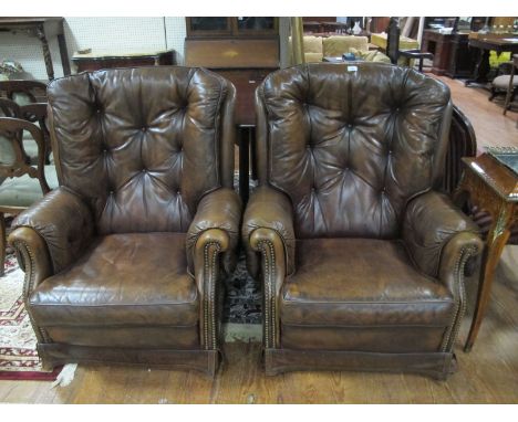 A GOOD PAIR OF HIDE UPHOLSTERED LIBRARY CHAIRS each with a deep button upholstered back with scroll arms and loose cushion on