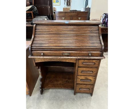 A 1930s oak roll-top desk, the tambour shutter over a flight of four drawers and recess. 36' wide