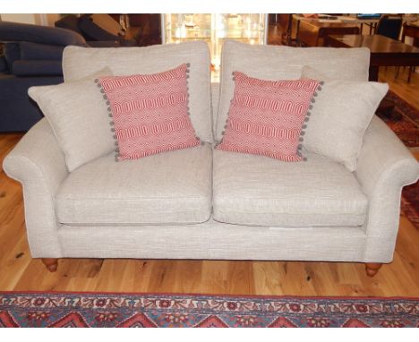 Modern two seat sofa, covered in oatmeal fabric and two red loose cushions and another oatmeal, 186cm w