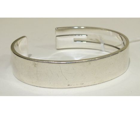 A Gucci silver bangle in the form of a stylised "G", marked "Gucci, Made in Italy", (remaining marks rubbed), 67g.