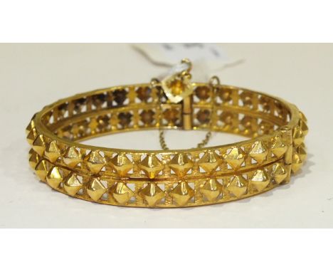 A yellow metal hinged bangle of two rows of hobnail bosses, unmarked, (tests as 14ct approx.), 31g.