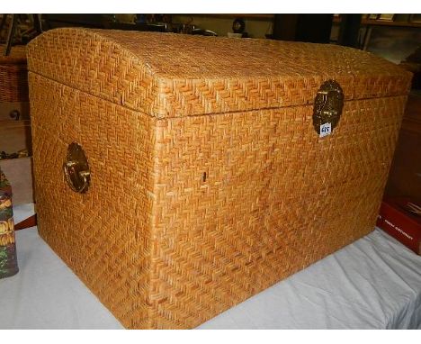 A dome topped wicker trunk with brass handles.