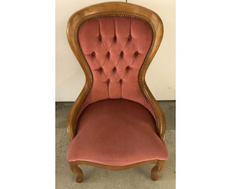A reproduction balloon back nursing chair with light wood frame and pink velvet upholstery.  