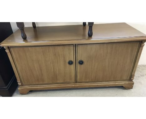 A light oak 2 door low TV unit on castors with internal shelving.  Approx. 108cm wide x 51cm tall.