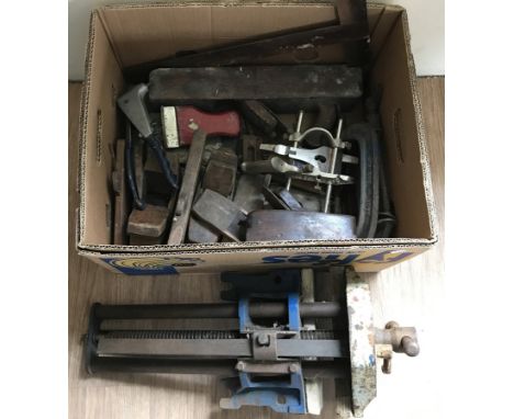 A box of vintage woodworking tools to include planes and clamps. Together with a carpenters bench vice. 