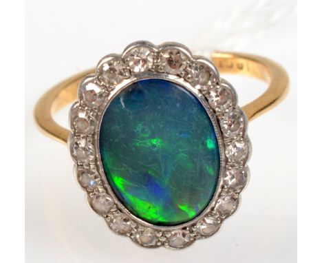 An 18ct. gold opal and diamond oval cluster ring.  Condition report: No cracks and one chip. 12 x 15mm at widest point. 
