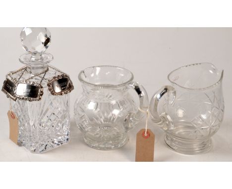 Two silver wine labels, a plated wine label, a cut glass spirit decanter and two cut glass jugs.