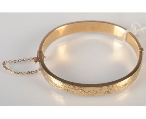 An engraved 9ct. gold hinged bangle, wax filled, 19g.  Condition Report: It is solid gold, it is hollow but has been filled w