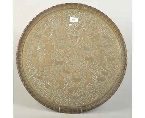 An Indo Persian circular brass tray engraved with a hunting scene including deer, figures with tiger heads, and huntsmen with