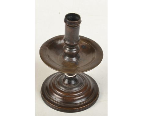 A 17th century Dutch brass Heemskerk candlestick with a central drip tray on a stepped foot, height 19cm.  A DUTCH BRASS HEEM