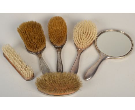 An engine turned silver mounted mirror and five silver mounted brushes.