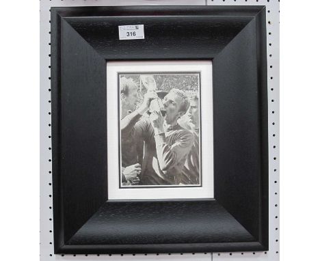 Bobby Moore Autograph, black pen signed (unverified) on a black and white image of him kissing the World Cup, unfortunately f