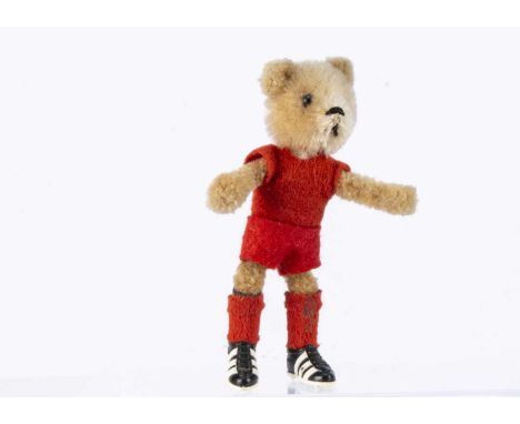 A Schuco post war teddy bear dressed as a footballer,  with blonde mohair head, metal pin eye (one missing), black stitched n