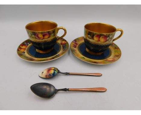 Royal Worcester - a pair of hand painted and gilt cups and saucers, each with Fruits pattern and central powder blue ground, 