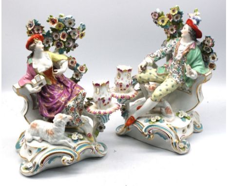 A pair of Samson porcelain candlestick figures of a gent and his lady companion, both seated before bocage, he with a bird on
