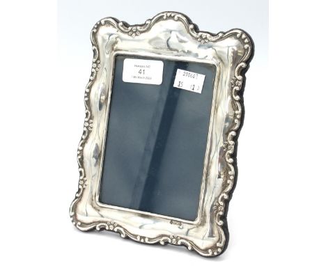 An Elizabeth II silver photograph frame, of scrolled shape with cast foliage border, with fabric easel back and glass to fron