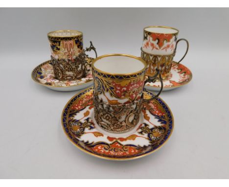 Three early 20th century Royal Crown Derby Imari type coffee cans and saucers, all with hallmarked silver mount holders, two 