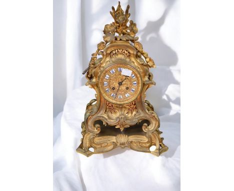 A 19th century ornate mantle clock, of elaborate scrolled shape in gilt metal, with cast foliage and floral detail, ornate gi
