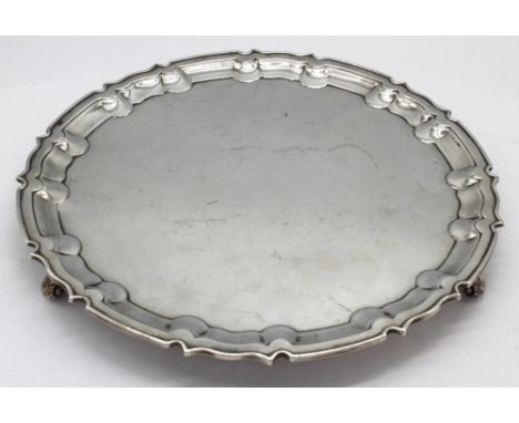 A George V silver salver, plain with raised pie crust rim, on three scroll feet, hallmarked by William Hutton & Sons., Sheffi