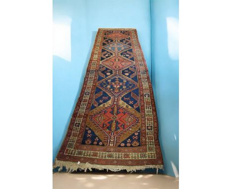 An Eastern wool runner, in decorative reds, blues and browns, tassel ends, approx. 335cm long x 93cm wide.