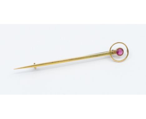 A synthetic ruby and 15ct gold bar brooch circa 1900, target form inset with a round mixed cut stone, length approx 65mm, tam