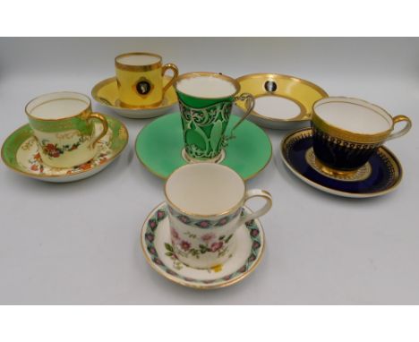 A collection of coffee cans and saucers comprising of a stylish unmarked green ground and gilt example, encased in hallmarked