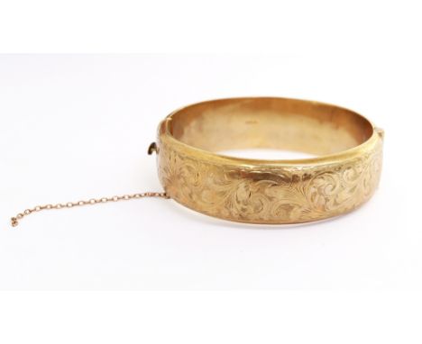 A 9ct yellow gold hinged bangle, with engraved decoration; width approx 18mm, weight approx 27gms  Further details: clasp not