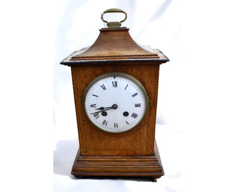 An Edwardian oak mantle clock, with body of rectangular shape with inlaid decoration, upon a stepped base plinth and stepped 