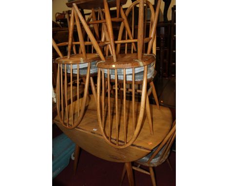 An Ercol light elm drop flap kitchen table, together with a set of six Ercol light elm stick back dining chairs (5+1) (7)No s