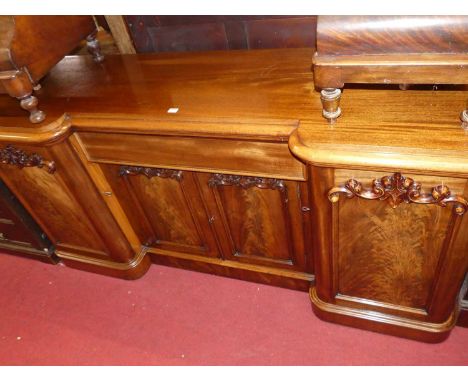 A mid-Victorian mahogany and flame mahogany round cornered inverted breakfront four door sideboard, having single frieze draw