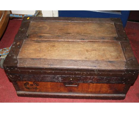 An early 20th century stained wood and metal bound hinge topped travelling trunk, having iron end carry handles, with galvani